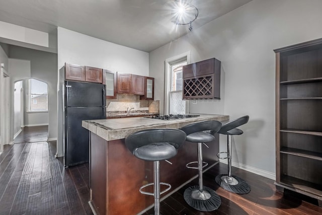 kitchen featuring a kitchen breakfast bar, dark wood finished floors, light countertops, and freestanding refrigerator