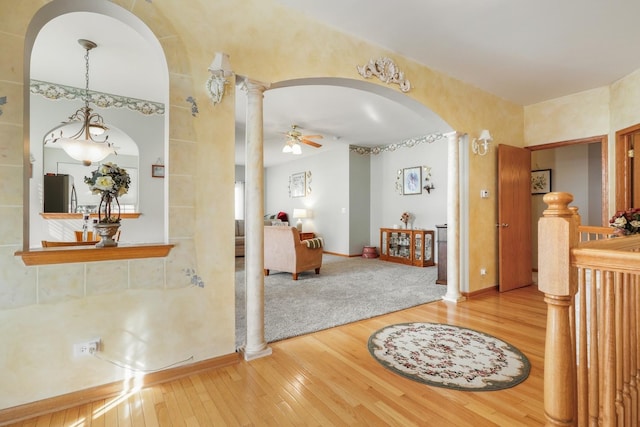 foyer entrance with hardwood / wood-style floors, decorative columns, and arched walkways