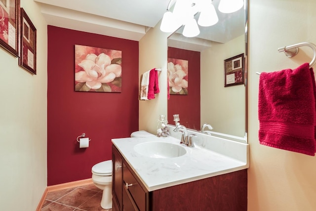 half bath with tile patterned floors, toilet, vanity, and baseboards