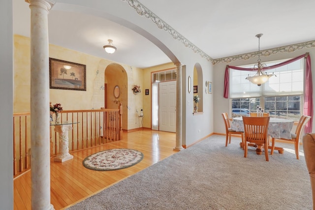 dining area with wood finished floors, arched walkways, carpet, decorative columns, and baseboards