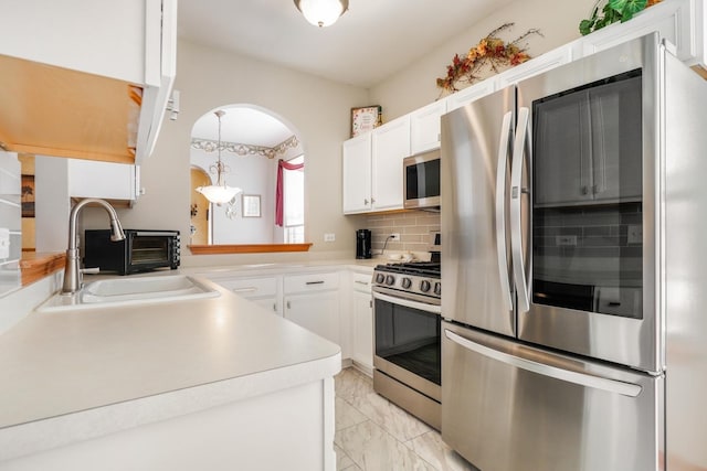 kitchen featuring a sink, white cabinetry, stainless steel appliances, light countertops, and decorative backsplash