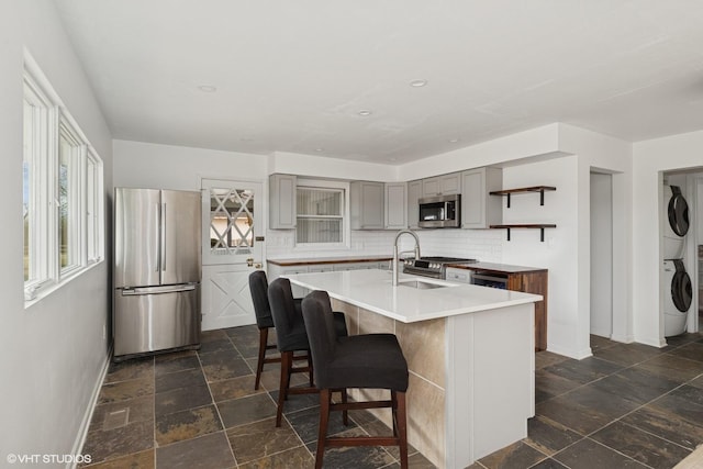 41660 N Hunt Club Rd, Old Mill Creek, IL 60083 - kitchen featuring open shelves, gray cabinets, a sink, stacked washer / dryer, and appliances with stainless steel finishes