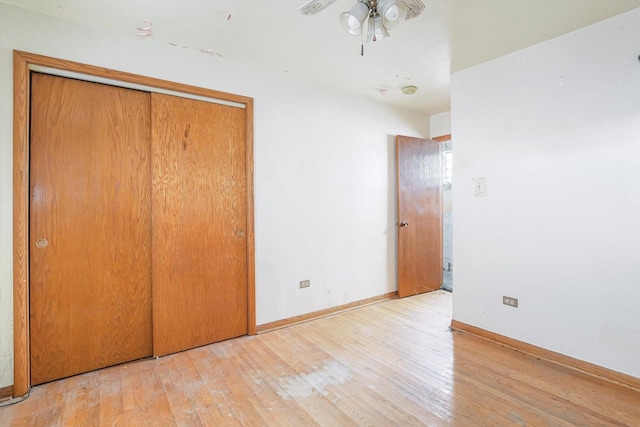 unfurnished bedroom with a closet, baseboards, and hardwood / wood-style flooring