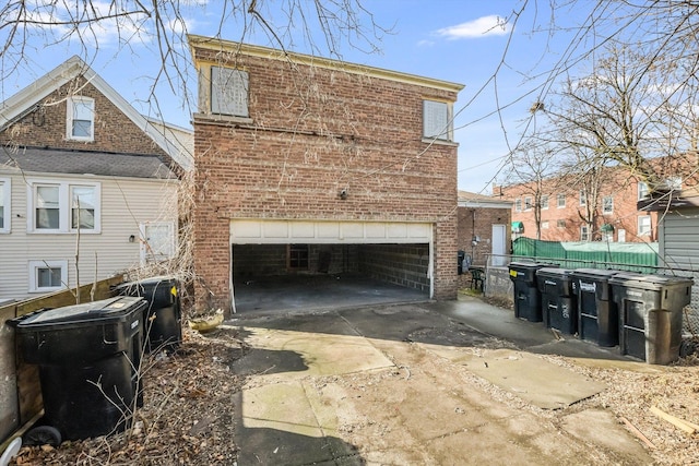 view of side of property with concrete driveway, fence, and brick siding