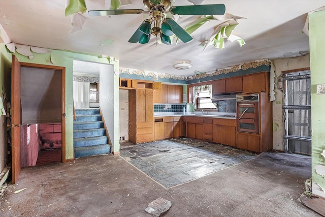 kitchen featuring light countertops, decorative backsplash, brown cabinets, a ceiling fan, and a sink