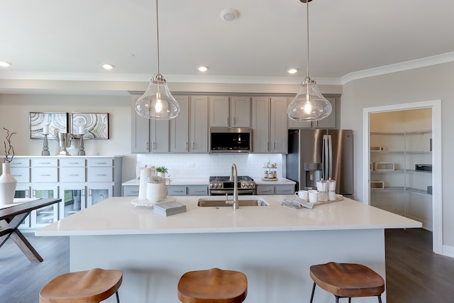 kitchen with a sink, a kitchen breakfast bar, appliances with stainless steel finishes, and gray cabinetry