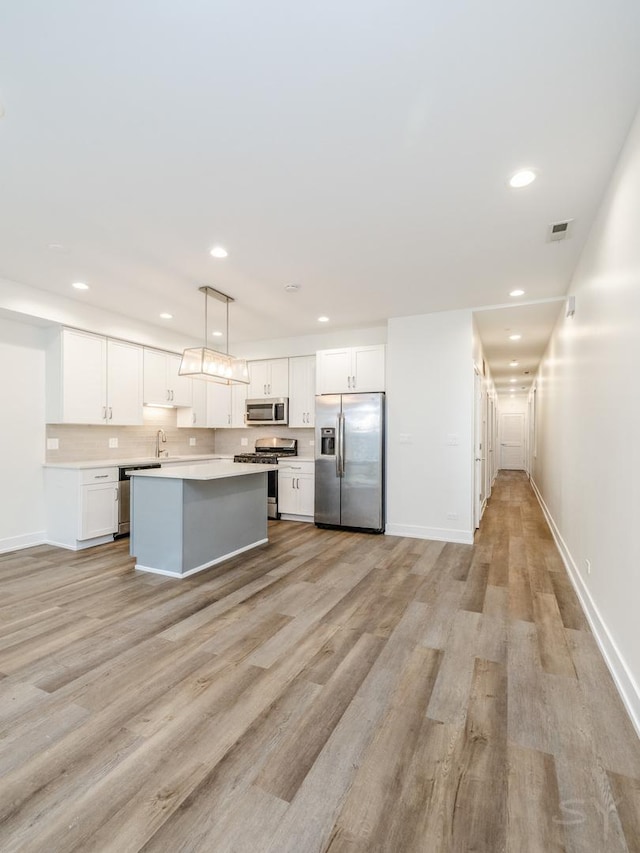 kitchen featuring visible vents, light wood-type flooring, a sink, white cabinetry, and appliances with stainless steel finishes