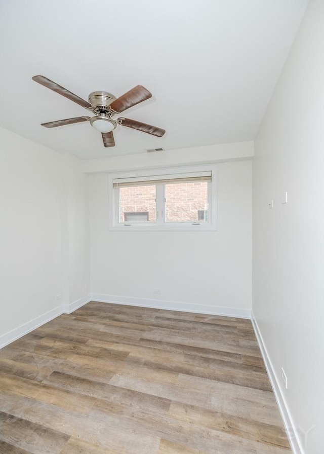 empty room featuring ceiling fan, visible vents, light wood-type flooring, and baseboards