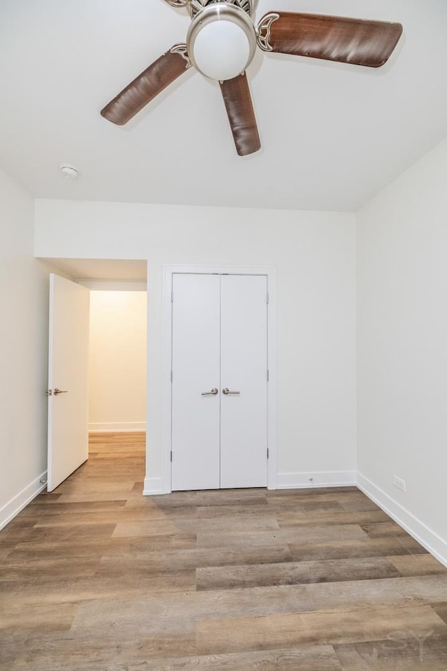 empty room with ceiling fan, baseboards, and wood finished floors