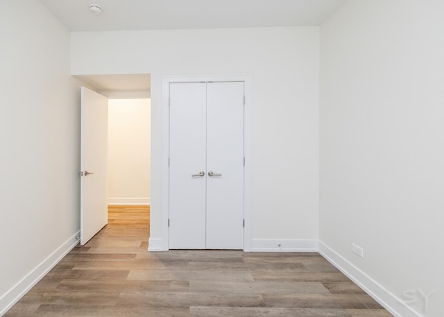 unfurnished bedroom featuring a closet, baseboards, and wood finished floors