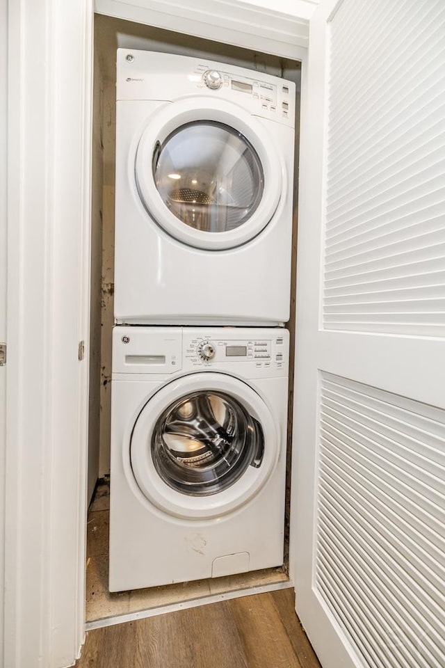 laundry area featuring laundry area, stacked washer / drying machine, and wood finished floors