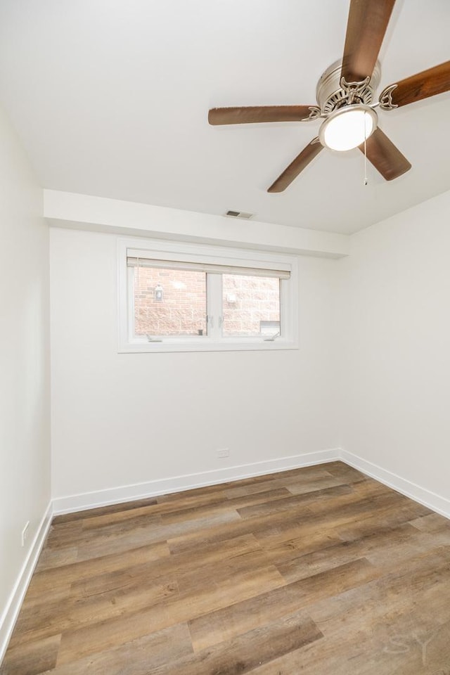 empty room featuring visible vents, wood finished floors, and baseboards