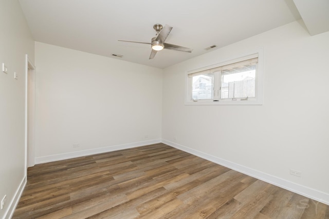 empty room with visible vents, ceiling fan, baseboards, and wood finished floors