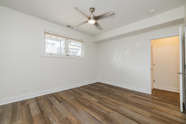 unfurnished room featuring dark wood-type flooring, visible vents, and baseboards