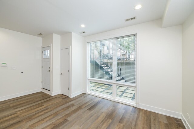 spare room with wood finished floors, visible vents, and baseboards