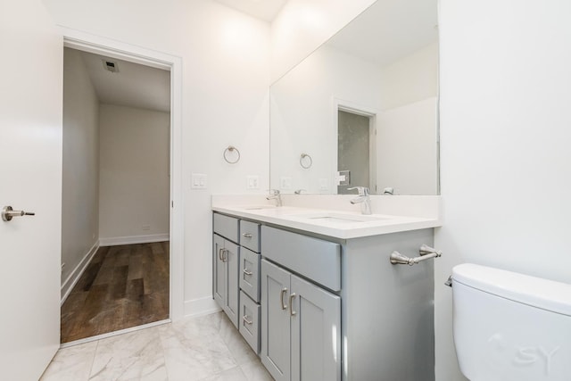 full bathroom with visible vents, toilet, marble finish floor, a sink, and double vanity