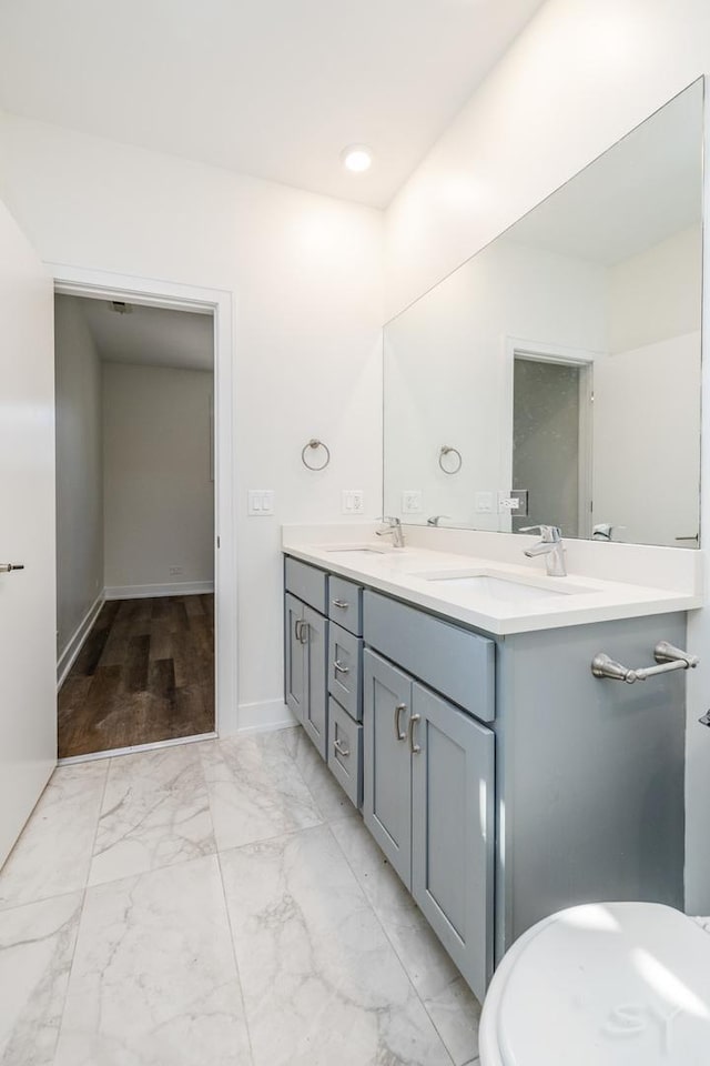 bathroom featuring double vanity, baseboards, marble finish floor, and a sink