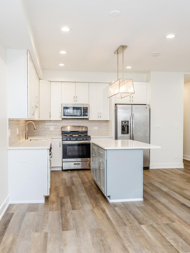 kitchen with a sink, stainless steel appliances, light wood finished floors, and light countertops