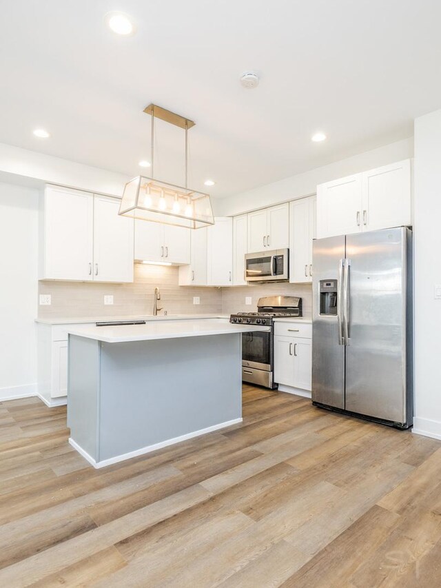 kitchen with light wood finished floors, appliances with stainless steel finishes, light countertops, and a sink