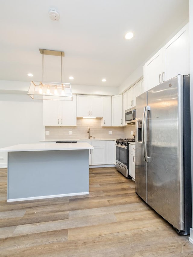 kitchen with stainless steel appliances, light wood-style floors, light countertops, and white cabinetry