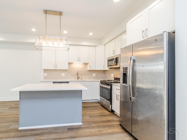 kitchen with backsplash, light wood-type flooring, light countertops, stainless steel appliances, and a sink