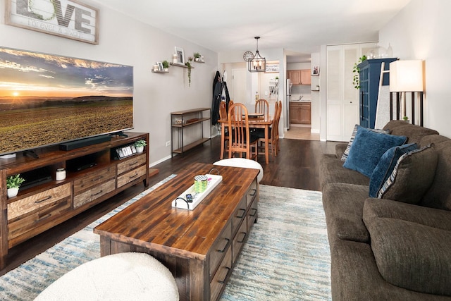 living area with a notable chandelier, dark wood-style floors, and baseboards