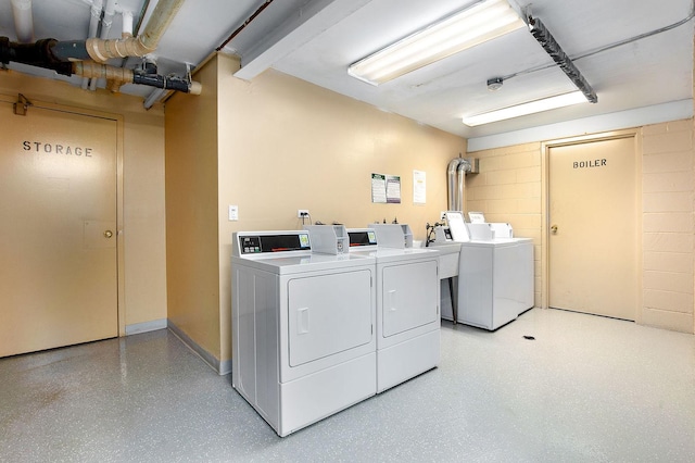 community laundry room with concrete block wall and washing machine and clothes dryer