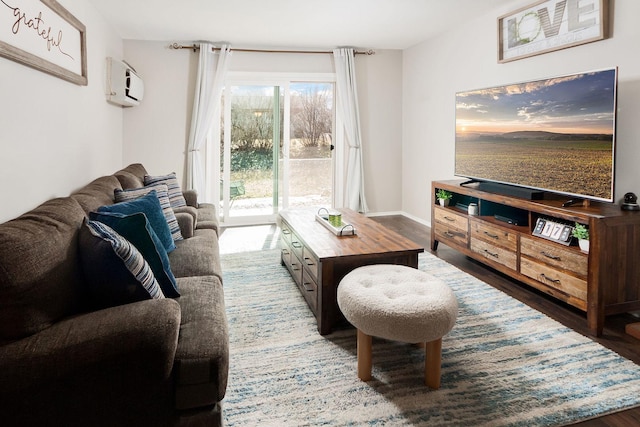 living area with wood finished floors, baseboards, and a wall mounted air conditioner