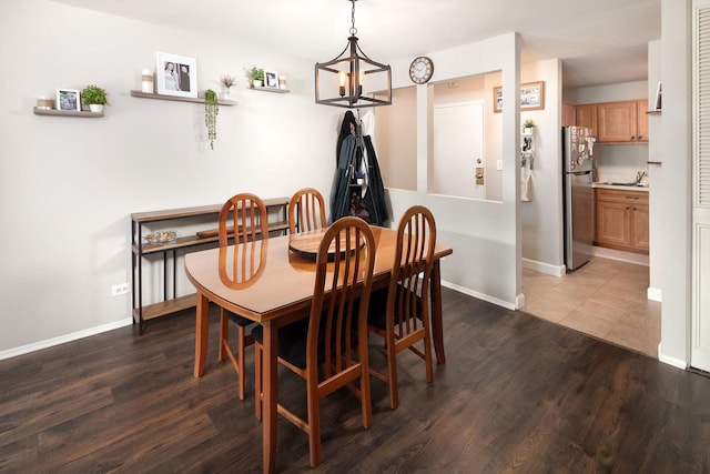 dining area featuring dark wood finished floors, baseboards, and a chandelier