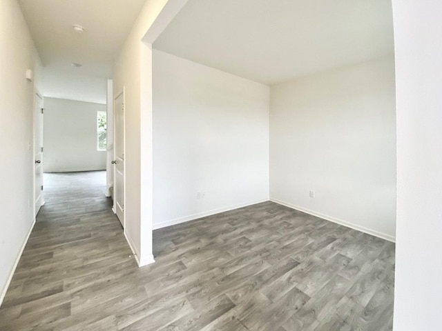 spare room with baseboards and wood finished floors