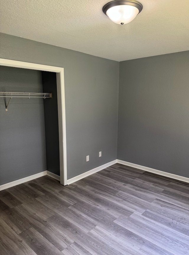 1312 N Hickory St, Champaign, IL 61820 - unfurnished bedroom with dark wood-style flooring, a closet, and a textured ceiling
