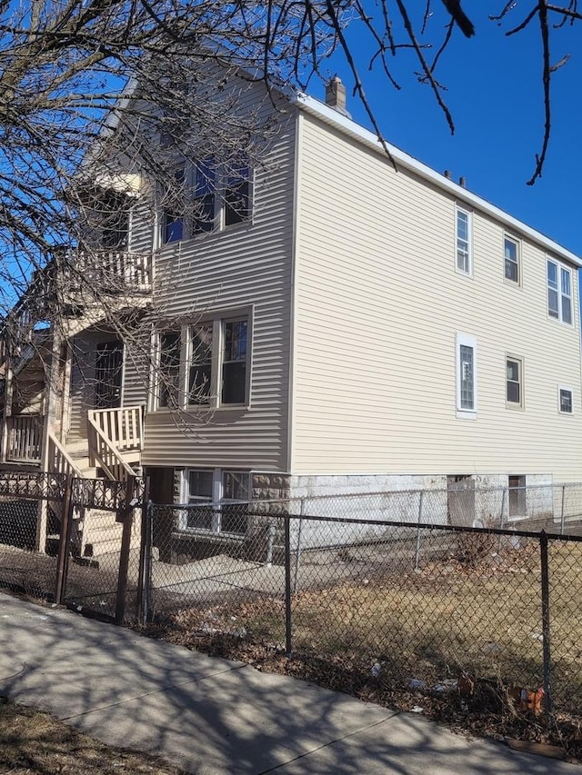 view of side of home featuring a balcony, fence private yard, and a chimney