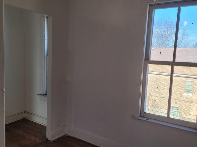 unfurnished room with baseboards and dark wood finished floors