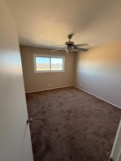 unfurnished room with dark carpet and ceiling fan