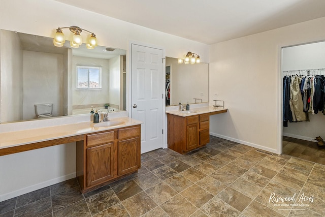 full bathroom with visible vents, stone finish floor, vanity, baseboards, and a spacious closet