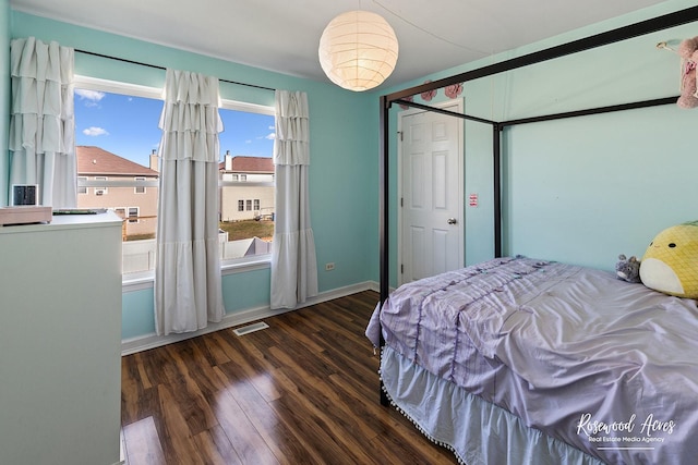 bedroom with wood finished floors, visible vents, and baseboards