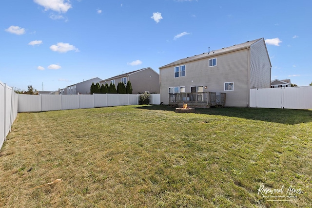 rear view of house featuring a lawn, a fenced backyard, and a fire pit