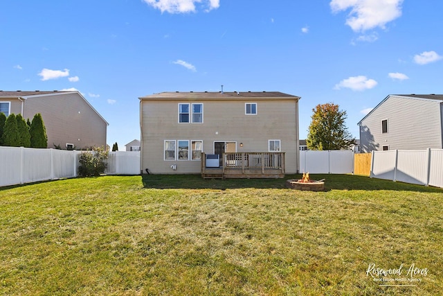 back of property with a yard, a fire pit, and a fenced backyard