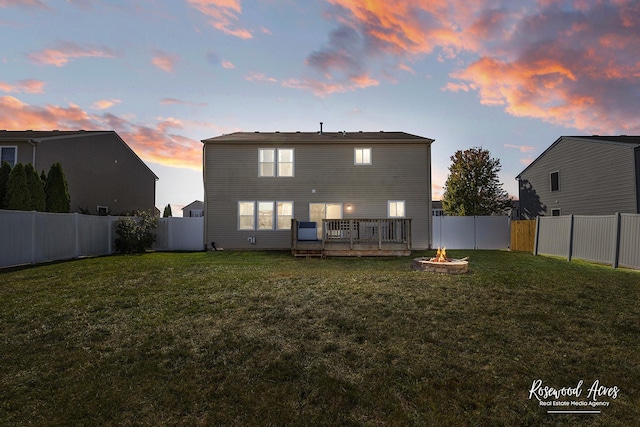 back of property with a lawn, a fenced backyard, and an outdoor fire pit