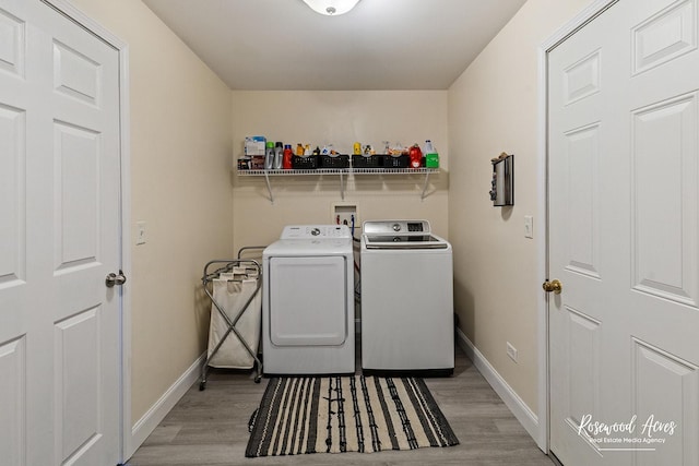 washroom featuring light wood finished floors, laundry area, independent washer and dryer, and baseboards