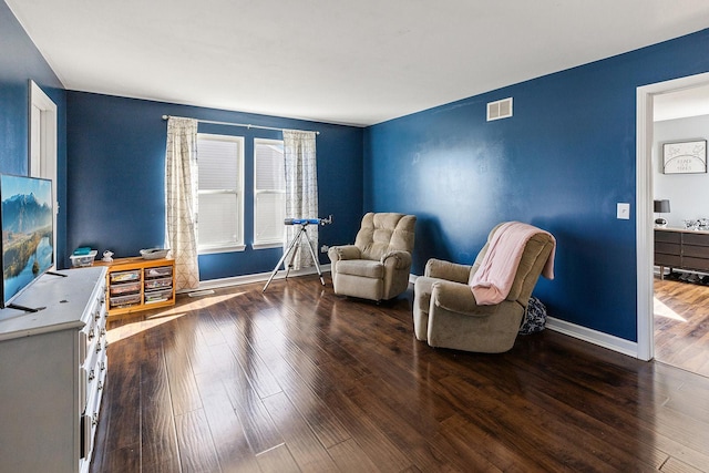 living area featuring visible vents, baseboards, and wood finished floors