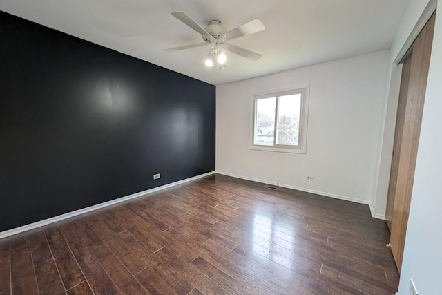 unfurnished bedroom featuring ceiling fan, dark wood-style floors, a closet, and baseboards