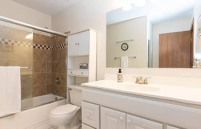 bathroom featuring toilet, vanity, and bath / shower combo with glass door