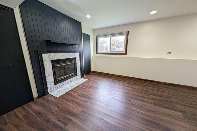 unfurnished living room with recessed lighting, a large fireplace, and dark wood finished floors