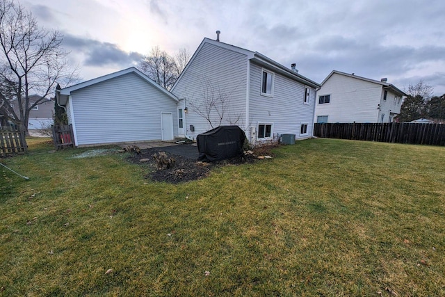 rear view of house with central air condition unit, a yard, and fence