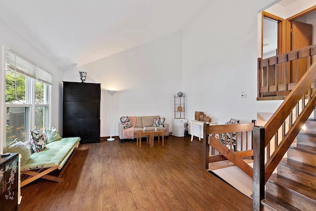 living area with stairway, wood finished floors, and high vaulted ceiling