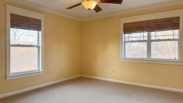 carpeted spare room with crown molding, a ceiling fan, and baseboards