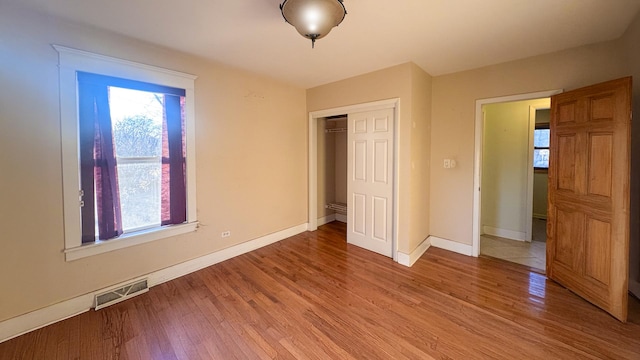 unfurnished bedroom featuring light wood-style flooring, baseboards, visible vents, and a closet