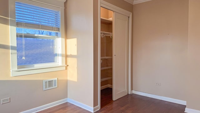 unfurnished bedroom featuring wood finished floors, visible vents, a closet, and baseboards