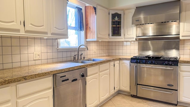 kitchen with light tile patterned floors, a sink, appliances with stainless steel finishes, wall chimney exhaust hood, and backsplash